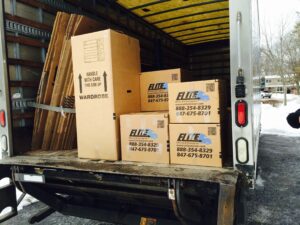 Elite logo cardboard moving boxes in back of open semi truck